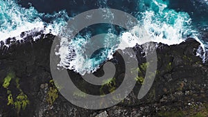 Aerial view of waves break on rocks of Faroe islands cliffs in a blue ocean.Drone Aerial Footage of green nature and the