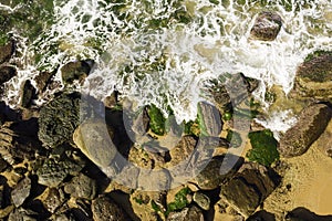 Aerial view of waves breaking on rocks at low tide