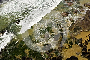 Aerial view of waves breaking on rocks at low tide