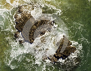 Aerial view of waves breaking on rocks with strong texture