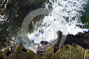 Aerial view of waves breaking on rocks with strong texture