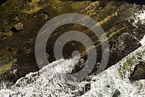 Aerial view of waves breaking on rocks with strong texture