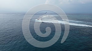 Aerial view of waves crashing onto a sunken barge with a crane