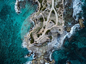 Aerial view of waves crashing on Punta Sur - Isla Mujeres, Mexico - with brilliant blue water, crashing waves and rocky shoreline.