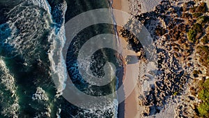 Aerial View of Waves Crashing on a Rocky Shoreline at Sunset