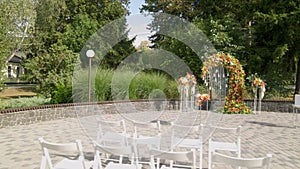Aerial view wedding ceremony with arch decorated with autumn leaves and flowers, white chairs for the guests, outdoor