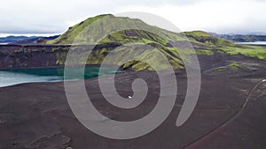 Aerial View White 4x4 Car Driving Offroad Dirt Road Ljotipollur Crater Iceland. Black Sand Lava Blue Emerald Lake Green