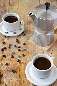 Aerial view of white cups with coffee and coffee pot, on rustic wooden table with coffee beans,