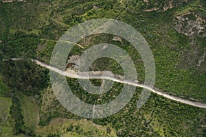 Aerial view of a white dirt road running along a steep hill covered in small bushes