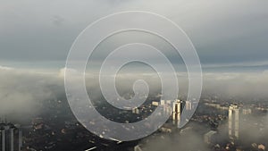 Aerial view of white fluffy clouds in bright blue sky with sunlight above a cityscape