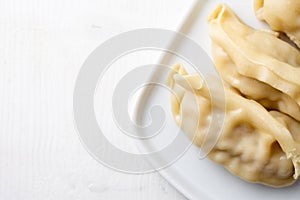 Aerial view of white plate with gyozas on white background, horizontally,