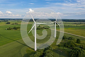 Aerial view of white wind turbines in green fields in summer