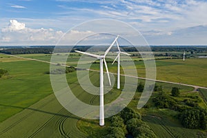 Aerial view of white wind turbines in green fields in summer