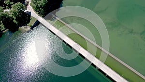 Aerial view of wide river with car bridge in a plain with crops, Aliakmonas river, Veria Greece, moving up and forward by drone