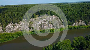 Aerial view of wild nature with rock clif and endless forest. Clip. Beautiful river along summer trees.