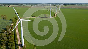 Aerial view of a wind farm in a rural landscape, featuring multiple wind turbines in a green field.