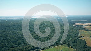 Aerial view of wind generators against smoking stacks of a traditional power plant. Green energy production, new and old