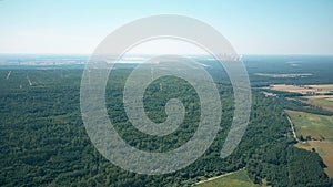 Aerial view of wind generators against smoking stacks of a traditional power plant. Green energy production, new and old