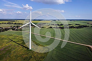 Aerial view of wind turbine and agricultural field, summer rural landscape. Wind power, sustainable and renewable energy