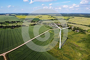 Aerial view of wind turbine and agricultural field, summer rural landscape. Wind power, sustainable and renewable energy