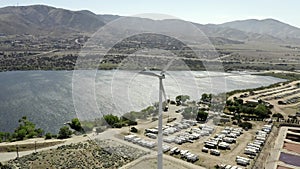 Aerial view of wind turbine spinning in wind at manufacturing plant, lake