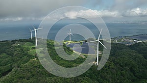 Aerial view of wind turbines and solar panels at green energy farm on coast