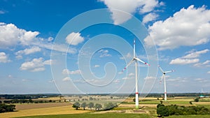 Aerial view of wind turbines windmills in farming fields against the sky with clouds. Alternative ecological energy production in