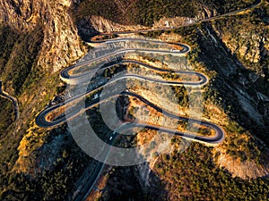 Aerial view of a winding mountain road, showcasing its sharp curves and rugged terrain