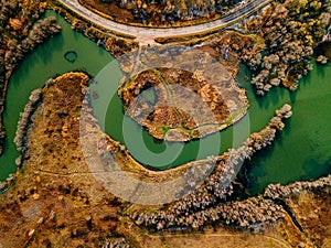 Aerial view of winding river and road in golden colored fall forest