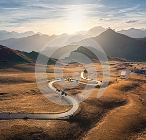 Aerial view of winding road in mountain pass, golden sunlight
