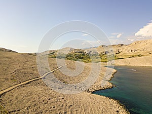 Aerial view of a winding road that runs along the Croatian coasts, dirt road, island of Pag near Rucica beach in Metajna. Croatia