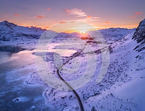 Aerial view of winding road, snow covered mountains at sunset