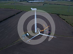 Aerial view of a windmill in a field and a yellow crane
