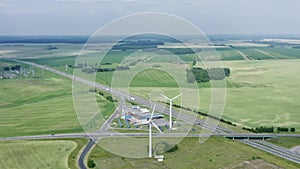 Aerial view windmills wind turbines producing clean ecological electricity by road in green agricultural fields in