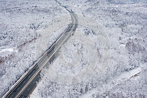 Aerial view of winter beautiful landscape road with trees covered with hoarfrost and snow. Winter scenery from above. Landscape