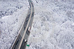 Aerial view of winter beautiful landscape road with trees covered with hoarfrost and snow. Winter scenery from above. Landscape