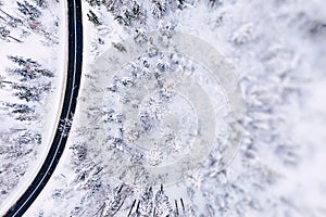 Aerial view of winter beautiful landscape road with trees covered with hoarfrost and snow. Winter scenery from above. Landscape