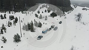 Aerial view of winter coniferous forest. Clip. snow falling on a rural road with parked cars near snow covered white