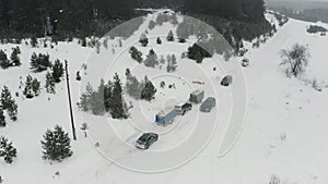 Aerial view of winter coniferous forest. Clip. snow falling on a rural road with parked cars near snow covered white