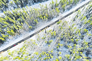 Aerial view of a winter country road in the forest with moving cars. Beautiful landscape. Captured from above with a drone. Aerial