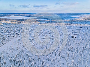 Aerial view of winter forest with frosty trees, rural road and village in Finland