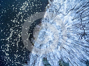 Aerial view of winter forest and ice drift on the river