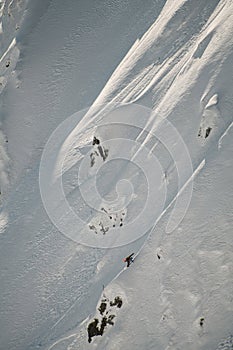 aerial view of winter mountain and brave man skier climbing up on it