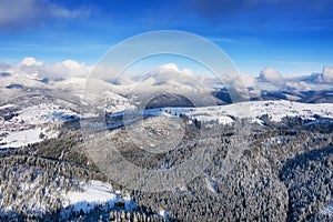 Aerial view at the winter mountains. Forest from air. Winter landscape from a drone. Snowy landscape.