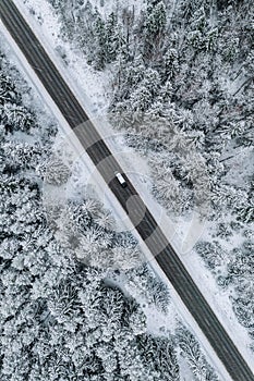 Aerial view of winter road with a car and snow covered forest in Finland