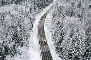 Aerial view of winter road with a car and snow covered forest in Finland