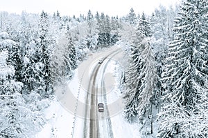 Aerial view of winter road with cars in snow covered forest