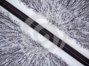 Aerial view of winter road and forest with snow covered trees
