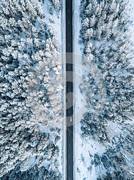 Aerial view of winter road and forest with snow covered trees in Finland