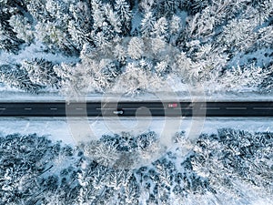 Aerial view of winter road and forest with snow covered trees in Finland